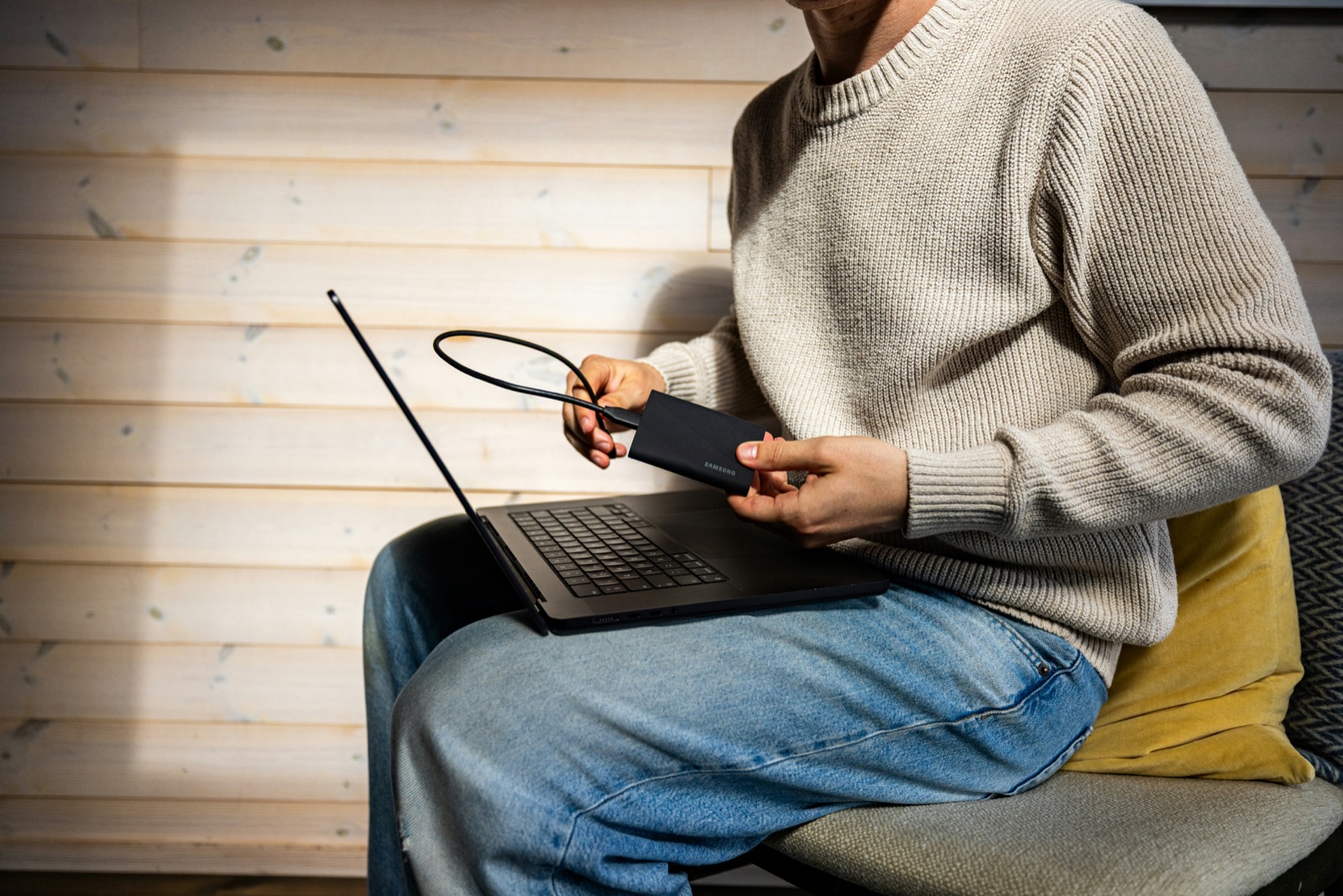 A person connecting a portable drive to a laptop